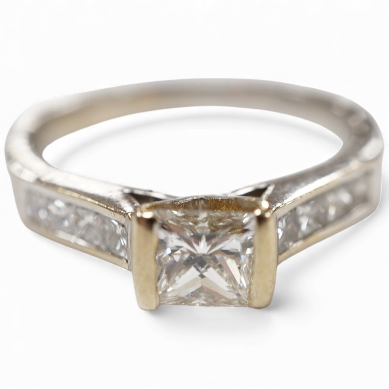 A diamond ring, set with a princess-cut diamond weighing approximately 0.40 carats, to shoulders channel-set with smaller princess-cut diamonds totalling approximately 0.40 carats, mounted in 18ct white gold, size K1/2,
